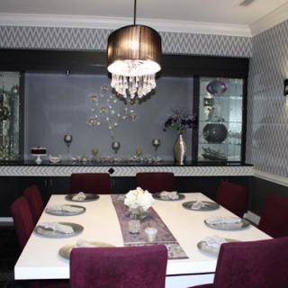 A beautifully designed dining room featuring a modern chandelier and elegant table settings.