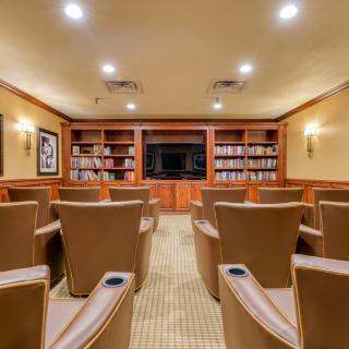 A cozy home theater with comfortable seating and bookshelves in a warmly lit room.