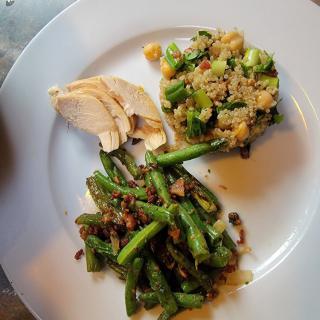 A plate featuring sliced chicken, a quinoa and vegetable mix, and seasoned green beans.
