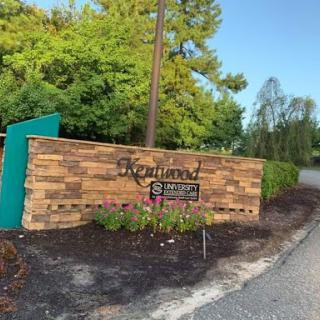 Welcome sign made of wood, surrounded by greenery.