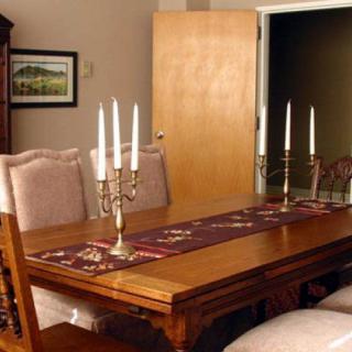 A dining room with a wooden table, chairs, and candlesticks as centerpiece decor.