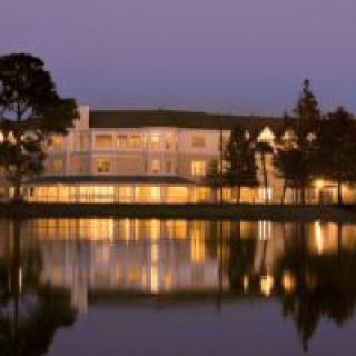 A building illuminated at night with its reflection on a calm body of water.
