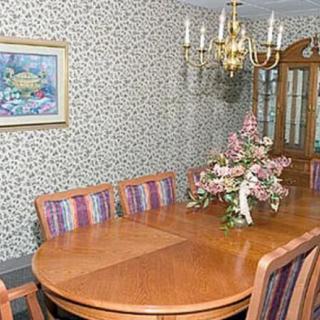 A traditional dining room with a wooden table, floral centerpiece, and patterned wallpaper.