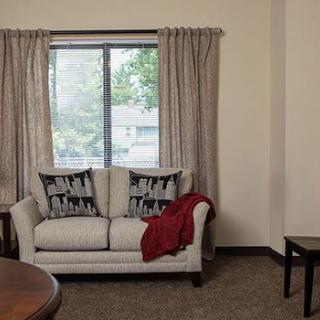 A cozy living room with a sofa and decorative cushions in front of a window with curtains.