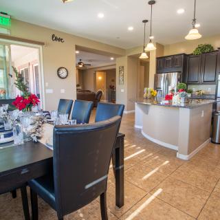 A modern kitchen and dining area with an open floor plan, featuring a kitchen island and pendant lighting.