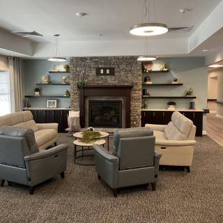 A cozy living room with a central fireplace, surrounded by comfortable seating and modern decor.