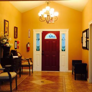 A warmly lit entrance hall with a red door and elegant chandelier.