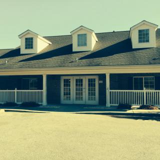A quaint single-story building with a porch and dormer windows.