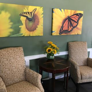 A cozy seating area featuring butterfly artwork and a vase of sunflowers.