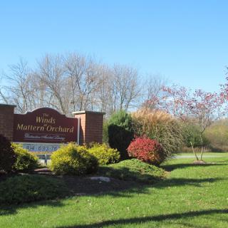 A welcoming sign surrounded by lush greenery and a clear blue sky.
