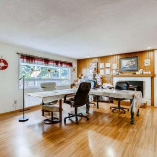 A spacious office with multiple workstations, featuring wooden floors and large windows.