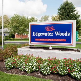 A sign for Edgewater Woods nursing home surrounded by well-maintained landscaping and flowers.