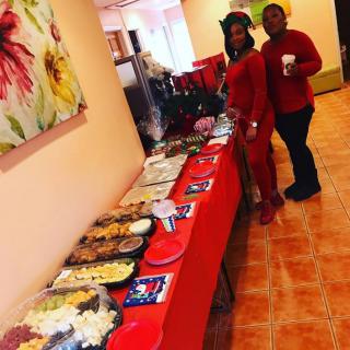 A buffet setup at a party with guests dressed in red.
