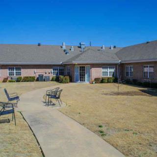 A residential building with a central courtyard featuring a pathway and seating area on a clear day.