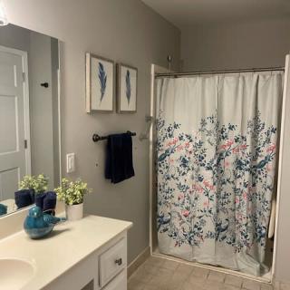 A neatly organized bathroom with floral shower curtain and decor.