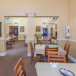 An indoor dining area with neatly arranged tables and chairs, illuminated by chandeliers.