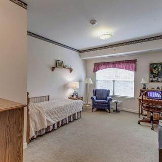 A cozy bedroom with a bed, chair, and desk by the window.
