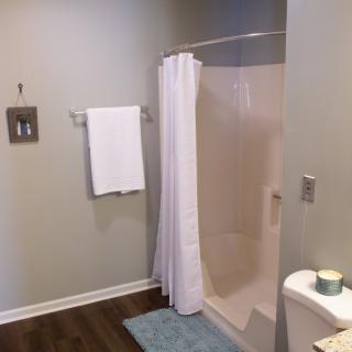 A modern bathroom with a shower, towel rack, and minimalist decor.