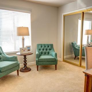 A cozy living room with teal armchairs and a large mirrored closet.