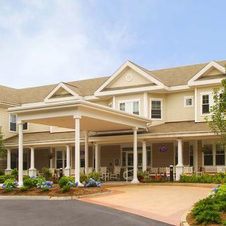 A large residential building with a porch and landscaped front yard.