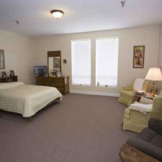 A spacious bedroom with a bed, dresser, and seating area.