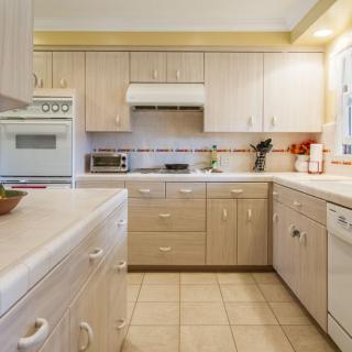 A modern kitchen with light wood cabinets and various appliances.