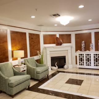 A cozy lobby area featuring green chairs, a fireplace, and elegant decor.