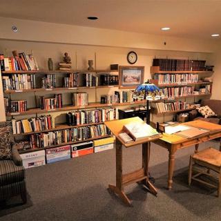 A cozy library corner with bookshelves, tables, and comfortable seating.
