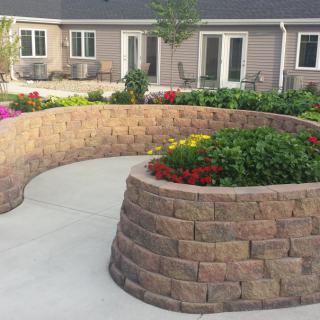A beautifully landscaped garden featuring a curved retaining wall with vibrant flower beds.