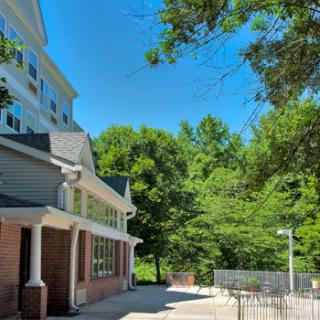 A sunny day with a building and lush green trees under a clear blue sky.