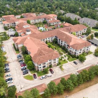 Aerial view of a residential complex surrounded by trees with parking areas.