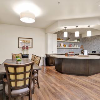 A modern open-concept dining and kitchen area with wooden flooring and pendant lighting.