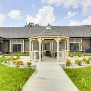 A beautiful gazebo surrounded by a landscaped garden and pathway leading to a building.