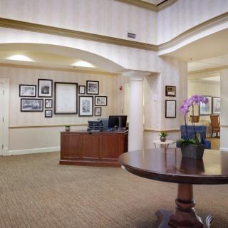 A welcoming reception area featuring a wooden desk, wall art, and a table with a flower vase.