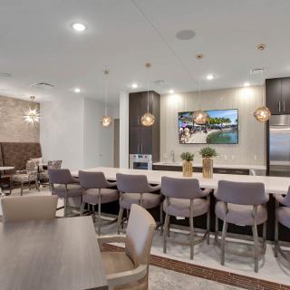 A modern kitchen with bar seating and pendant lighting, featuring an open dining area.