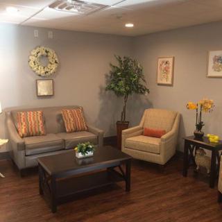 A cozy living room with a sofa, armchair, and coffee table, adorned with decorative elements and artwork.