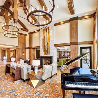 A luxurious living room with a grand piano, high ceilings, and elegant decor.