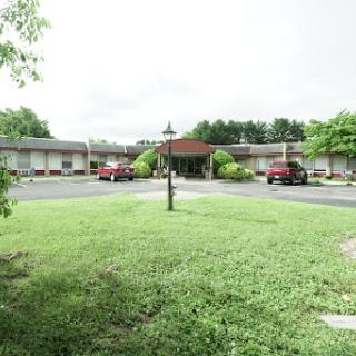 A quaint motel surrounded by lush greenery and a spacious parking area.