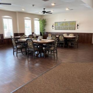 A spacious dining area with multiple tables and chairs, featuring ample natural light from the windows.
