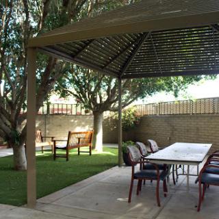 A serene garden setting featuring a gazebo, outdoor table, and comfortable seating.