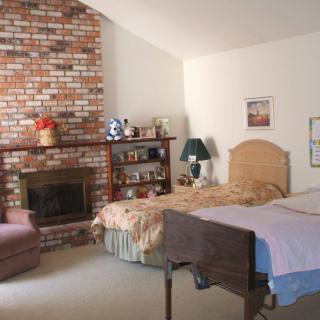 A cozy bedroom featuring a brick fireplace, a bed, and various furnishings.
