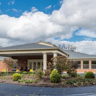 A brick building with a landscaped entrance under a cloudy sky.
