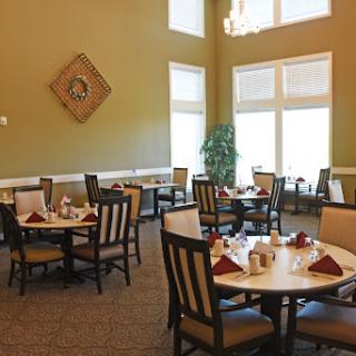 A cozy dining area with well-set tables, surrounded by large windows allowing natural light to fill the space.
