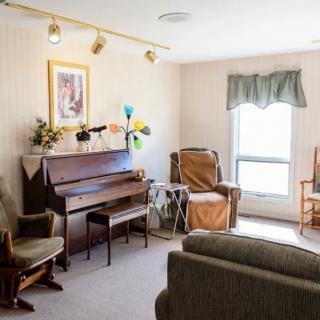 A cozy living room with a piano, comfortable armchairs, and a sofa.