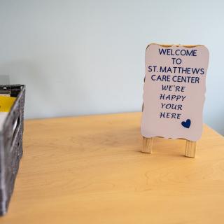 Welcome sign at St. Matthews Care Center on a wooden table.