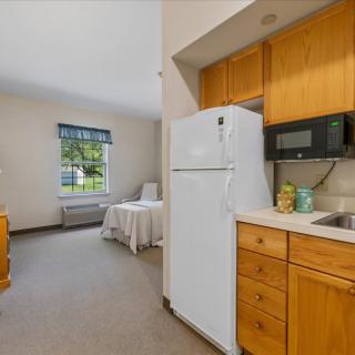 A cozy apartment kitchen with wooden cabinets, a white fridge, and a microwave.