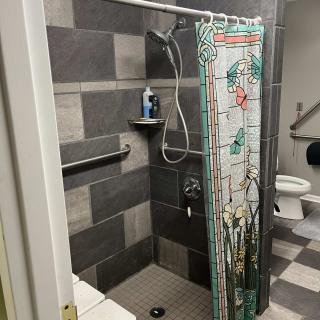 A modern bathroom with a tiled shower and colorful curtain.