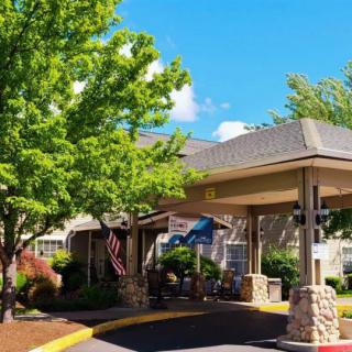 A welcoming entrance with a covered driveway and surrounding greenery.