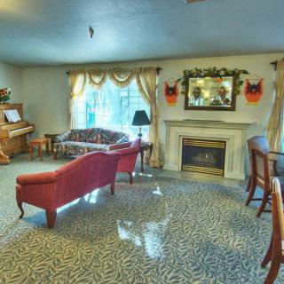 A cozy living room with a piano, red couch, and fireplace.