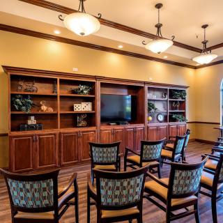 A conference room with arranged seating, a television on wooden shelves, and overhead lighting.